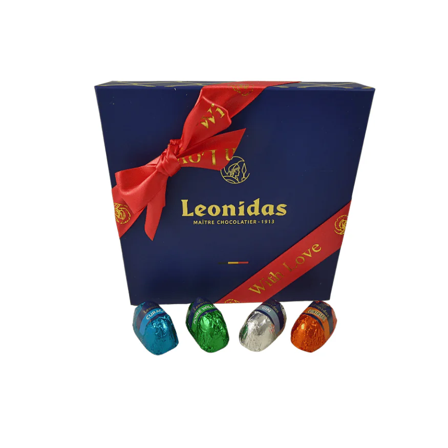 A small Leonidas gift box with a red wood love ribbon and liquors in front of it.