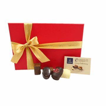 A top view of a red jewellery gift box wrapped with a gold leonidas ribbon with chocolates in front.