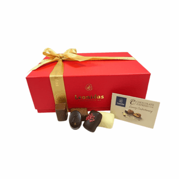 A red gift box wrapped with a gold Leonidas ribbon with chocolates displayed in front.