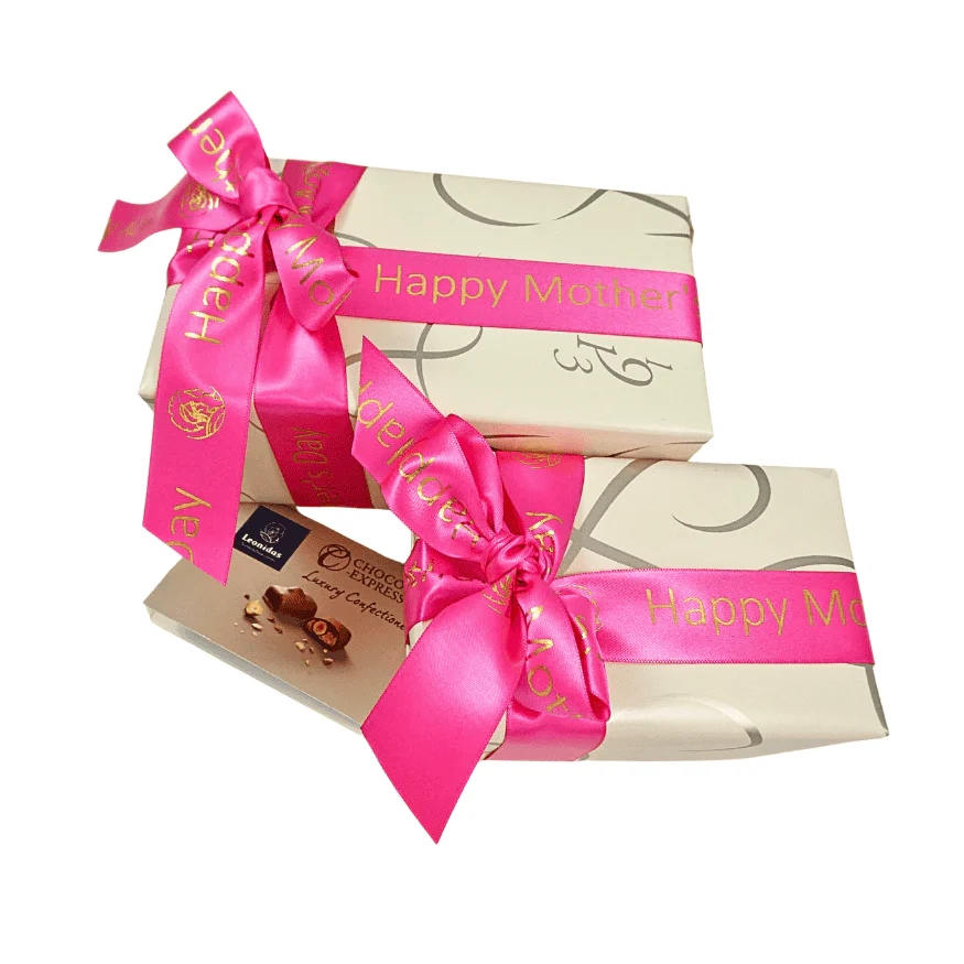 A Top View Of Two boxes of Leonidas chocolates in champagne-coloured paper, and both with Mother's Day ribbon. One box is bigger than the other.