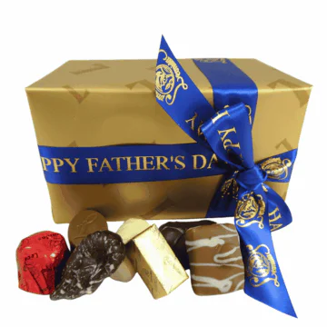 gold box of leonidas chocolates wrapped with a fathers day ribbon with chocolates in front