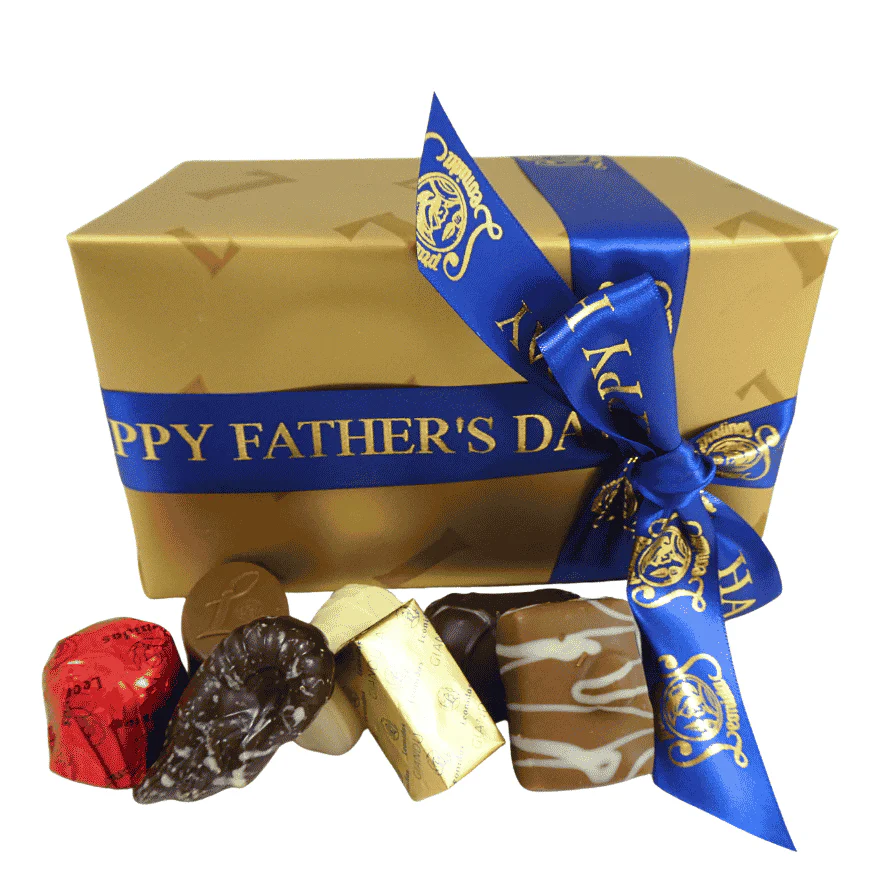 gold box of leonidas chocolates wrapped with a fathers day ribbon with chocolates in front