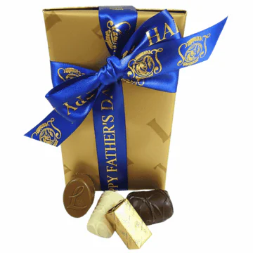 gold box of leonidas chocolates wrapped with a fathers day ribbon with chocolates in front